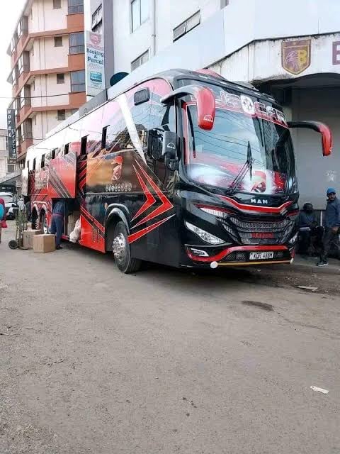 Red and black MAN tour bus parked on a street in front of residential buildings