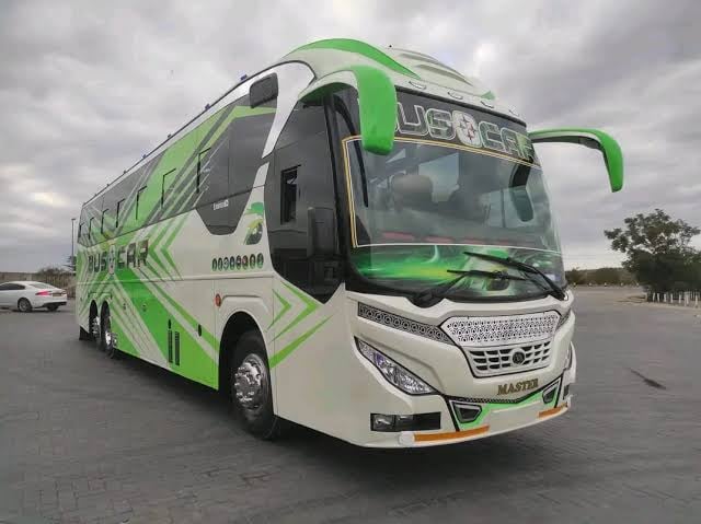 Green and white luxury intercity bus parked in a lot with cloudy sky