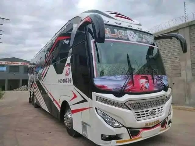 Red and white intercity coach bus parked at a depot with cloudy sky